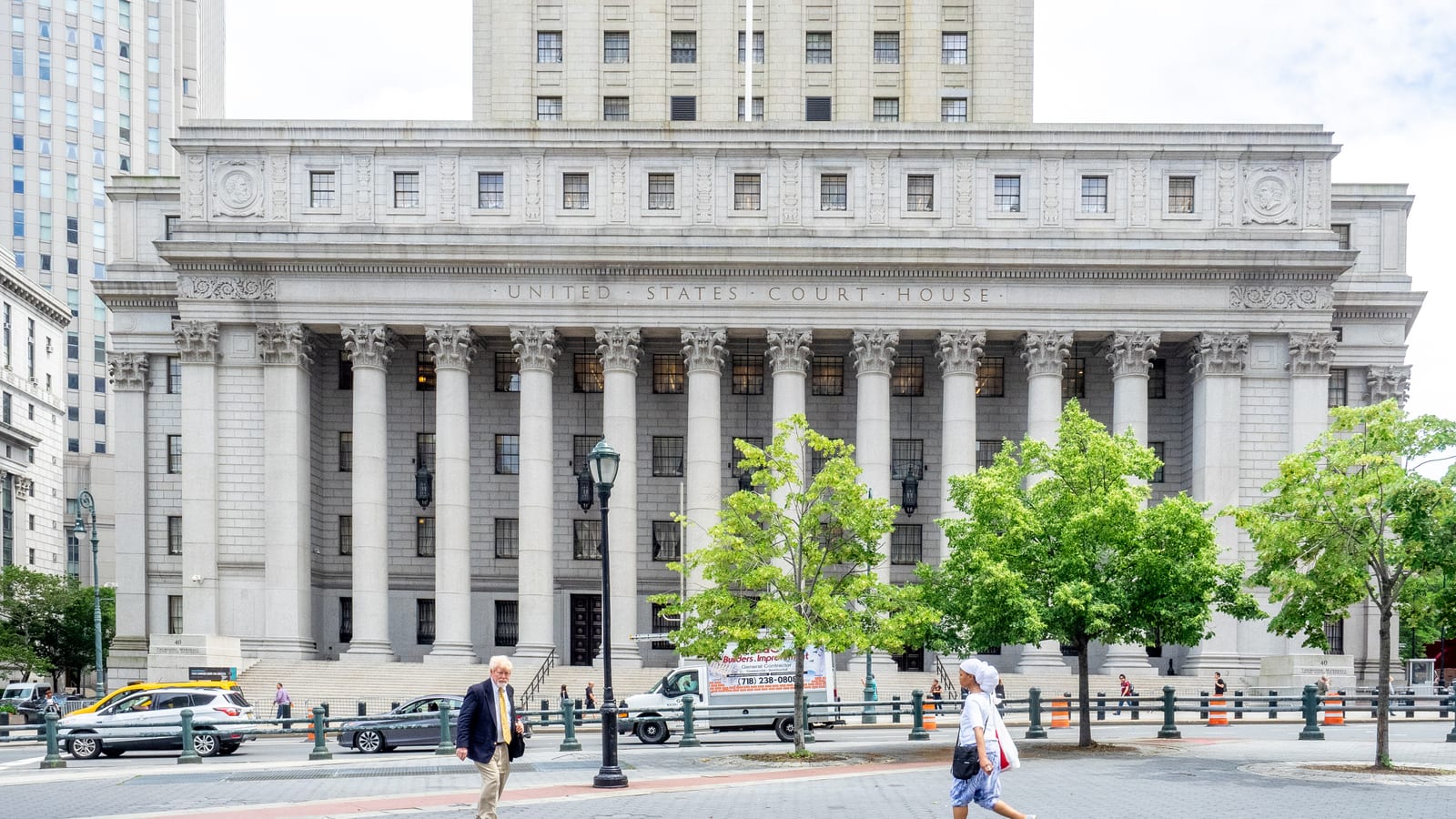 The colonnaded granite front of the Thurgood Marshall United States Courthouse, with its United States Court House inscription and the tower rising behind, seen across the street with pedestrians passing.